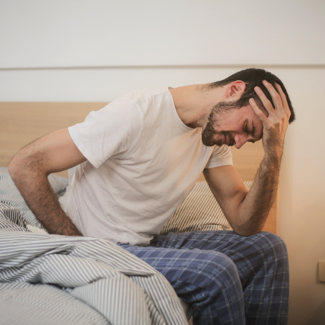 Man experiencing fatigue and headache from causes of iron deficiency