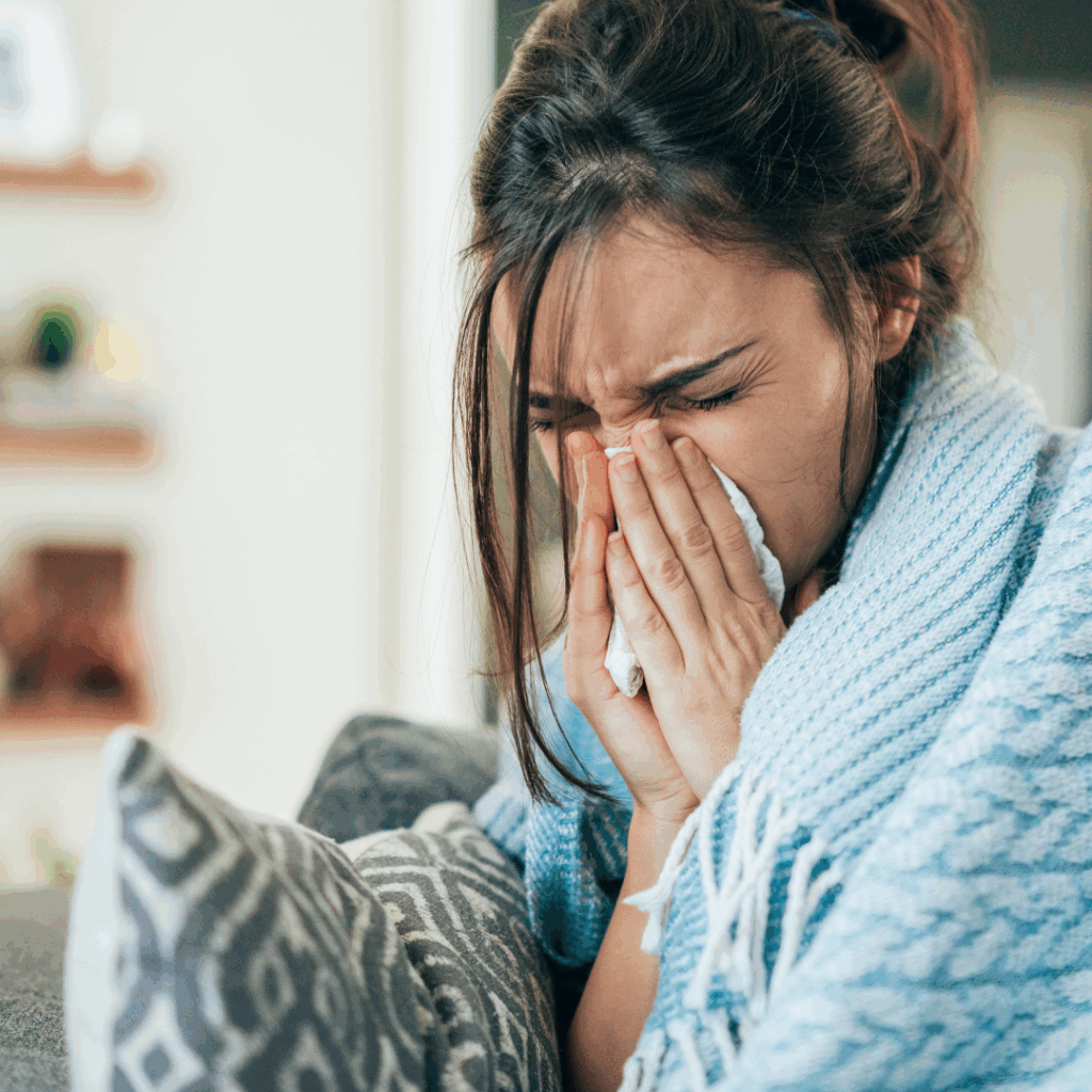 A sick woman wrapped in a blanket and sneezing