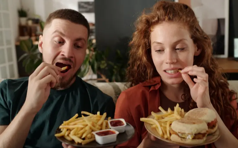 Couple eating fast food including french fries and burgers